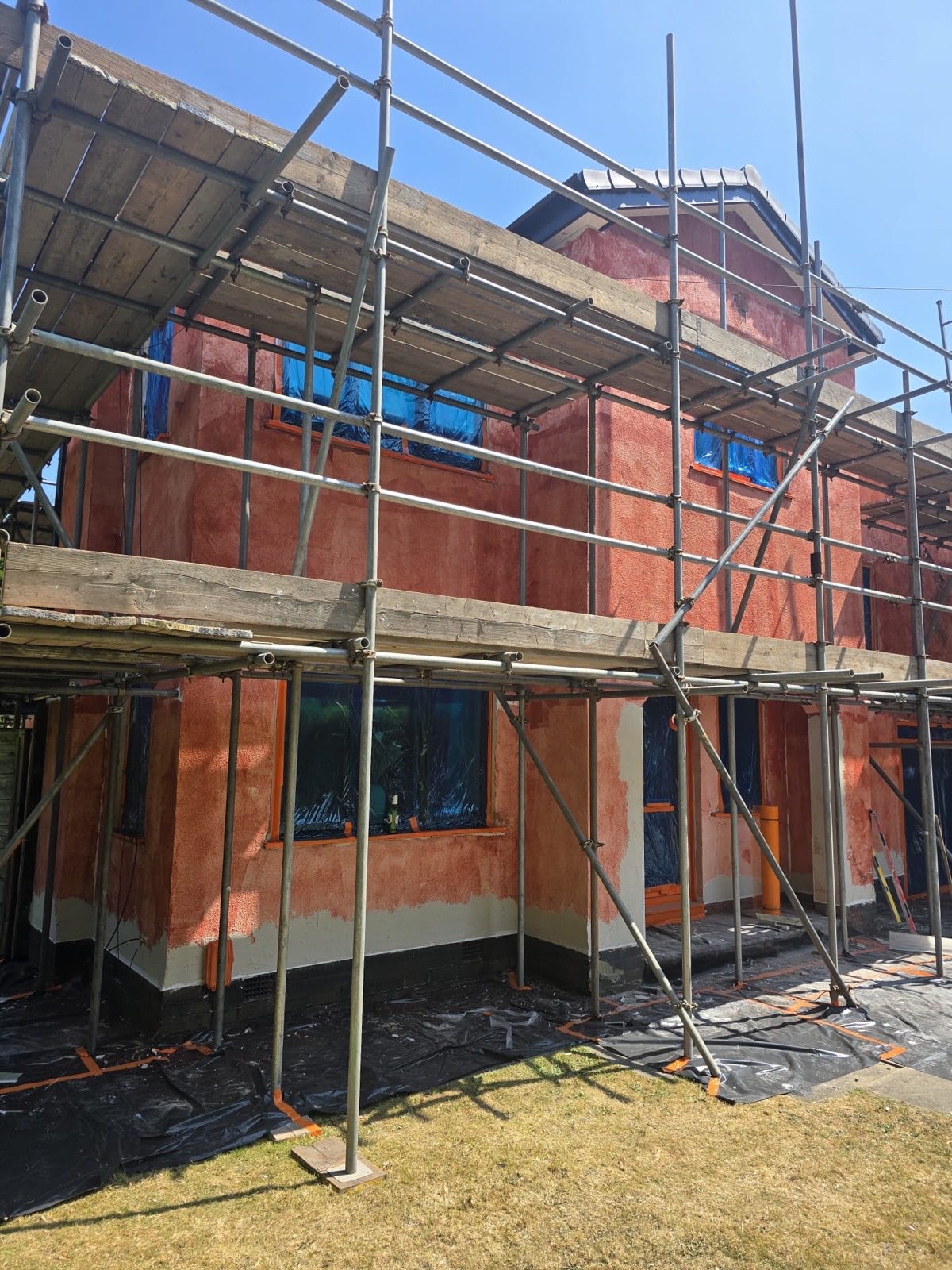Full house at basecoat stage — windows protected, render built up ready for topcoat